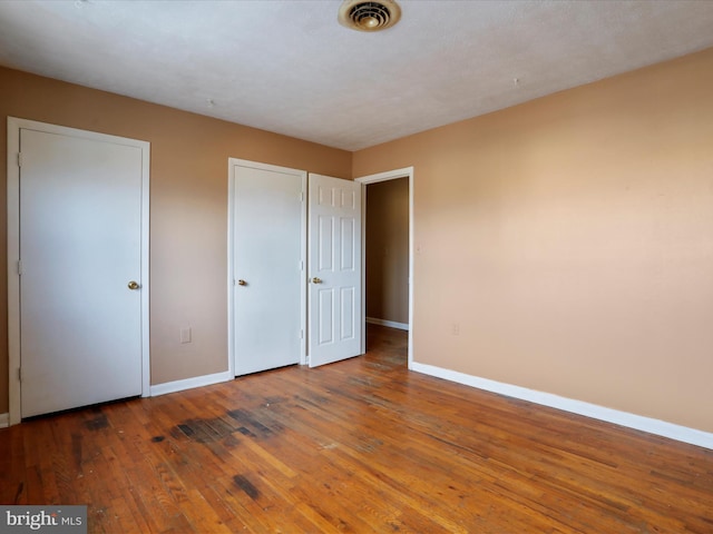 unfurnished bedroom with dark hardwood / wood-style flooring