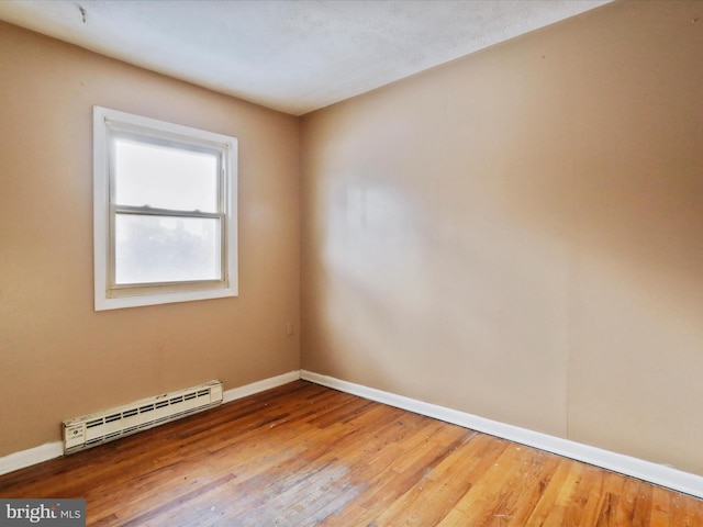 unfurnished room featuring hardwood / wood-style flooring and a baseboard heating unit