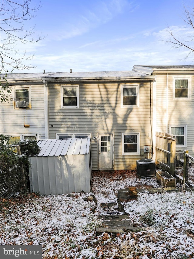 snow covered property featuring a storage shed and central AC