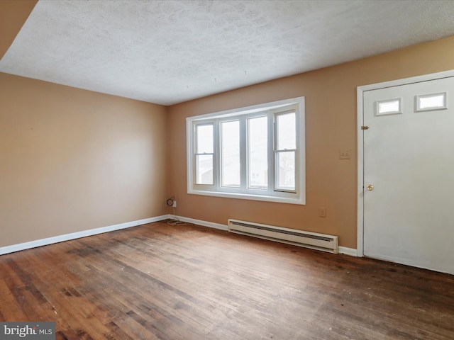 foyer with baseboard heating, hardwood / wood-style floors, and a textured ceiling