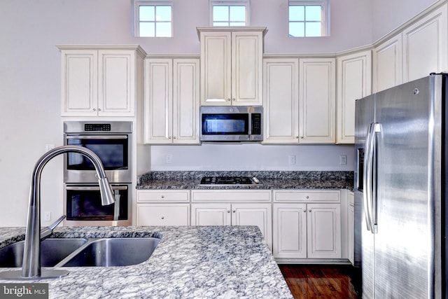 kitchen with sink, dark stone counters, and appliances with stainless steel finishes