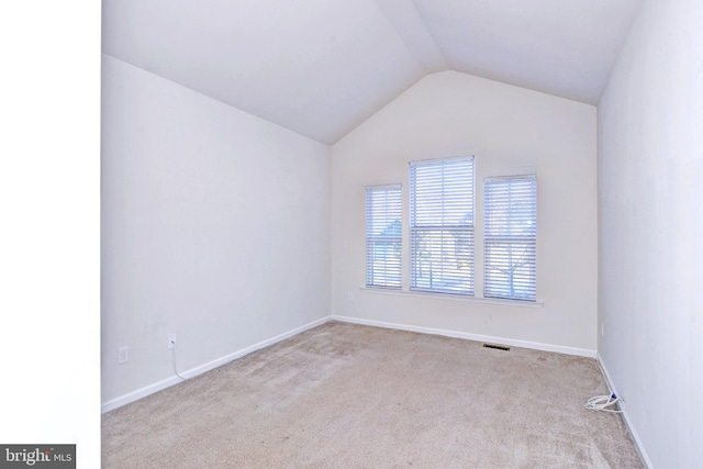 spare room featuring light carpet and lofted ceiling