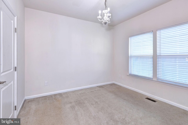 carpeted empty room featuring a notable chandelier