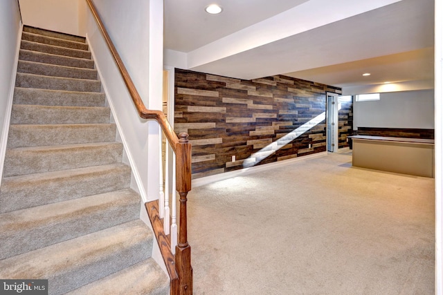 stairs with carpet flooring and wooden walls