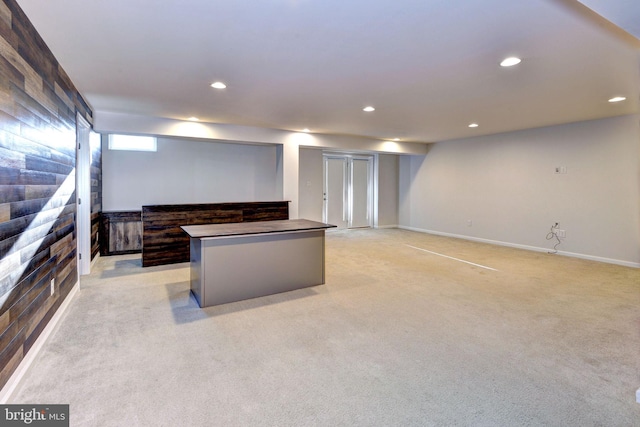 kitchen featuring a kitchen island, dark brown cabinetry, and light carpet