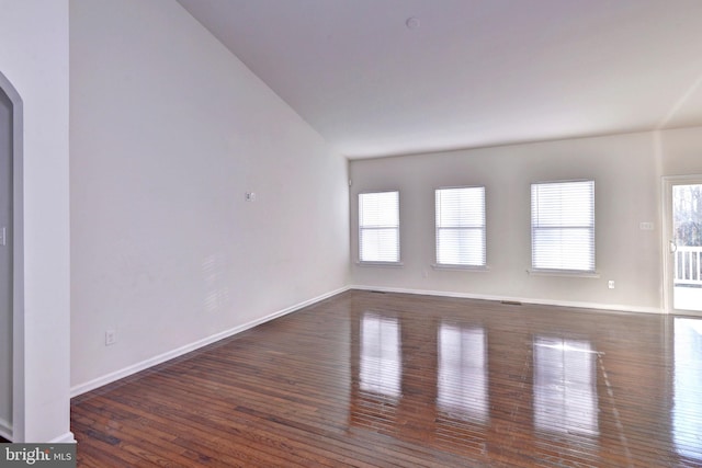 spare room featuring vaulted ceiling and dark hardwood / wood-style floors