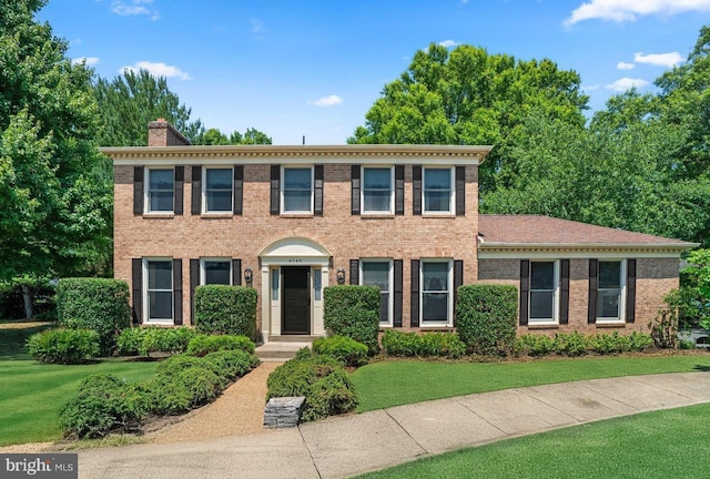 colonial-style house featuring a front yard