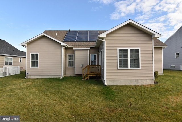 rear view of property with solar panels and a yard