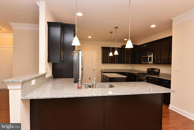 kitchen featuring sink, stainless steel appliances, light stone counters, kitchen peninsula, and pendant lighting