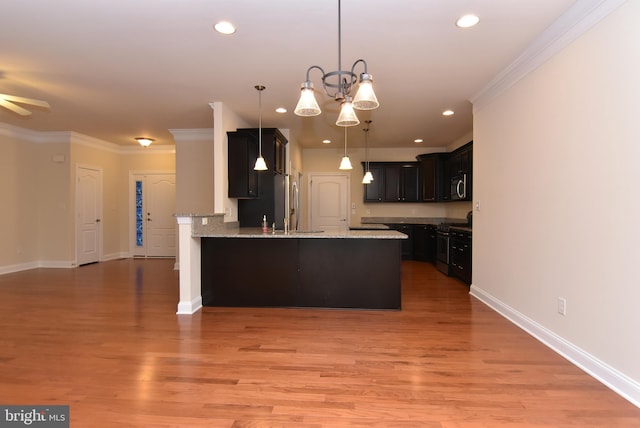 kitchen with black range, crown molding, hanging light fixtures, light stone countertops, and kitchen peninsula