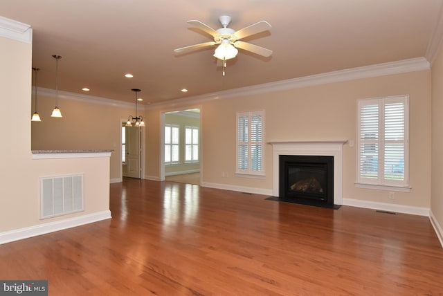 unfurnished living room with ceiling fan with notable chandelier, wood-type flooring, and crown molding