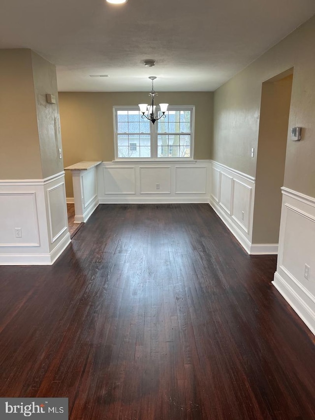 unfurnished dining area with dark hardwood / wood-style floors and an inviting chandelier