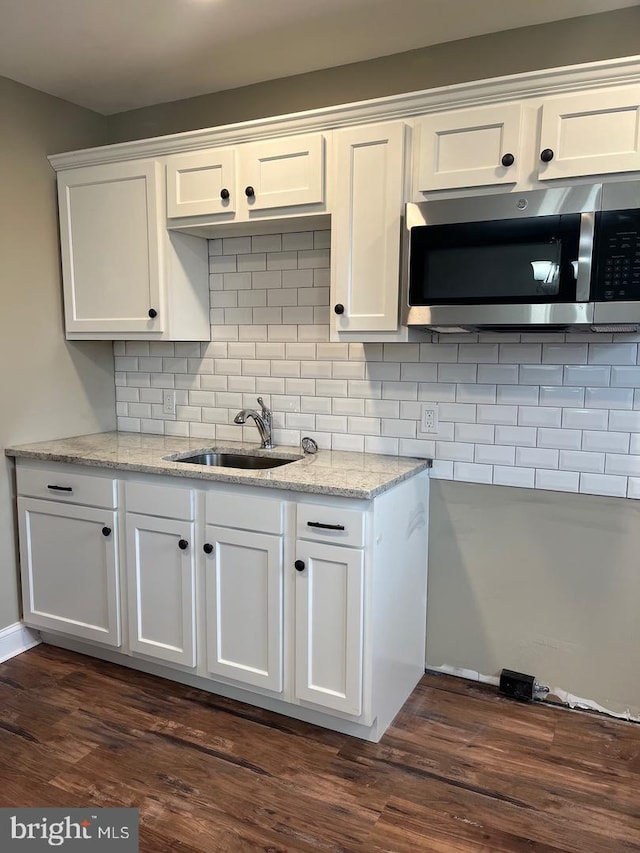 kitchen with white cabinets, sink, dark hardwood / wood-style floors, light stone countertops, and tasteful backsplash