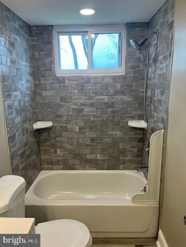 bathroom with toilet and tiled shower / bath