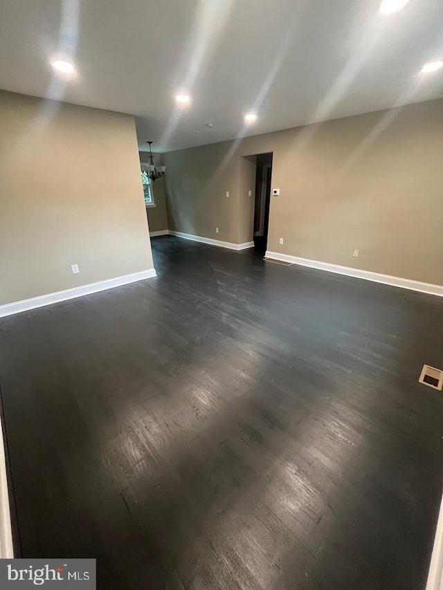 empty room with dark hardwood / wood-style floors and an inviting chandelier