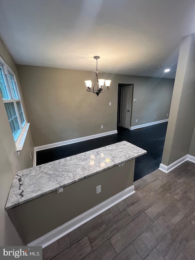 interior space with an inviting chandelier, hanging light fixtures, and light stone counters