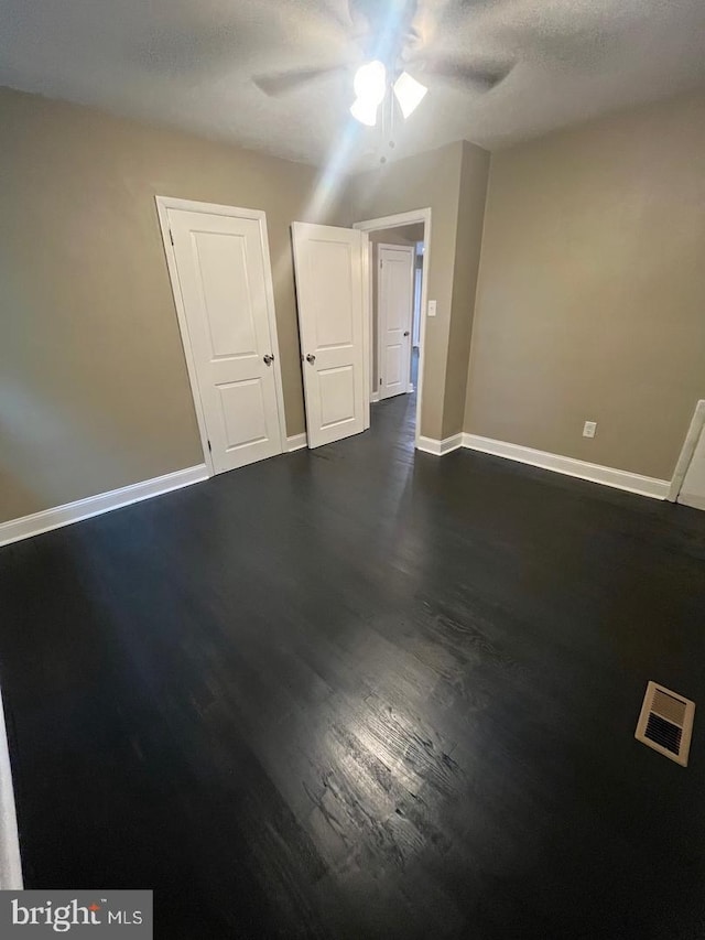 unfurnished room featuring a textured ceiling, ceiling fan, and dark hardwood / wood-style floors