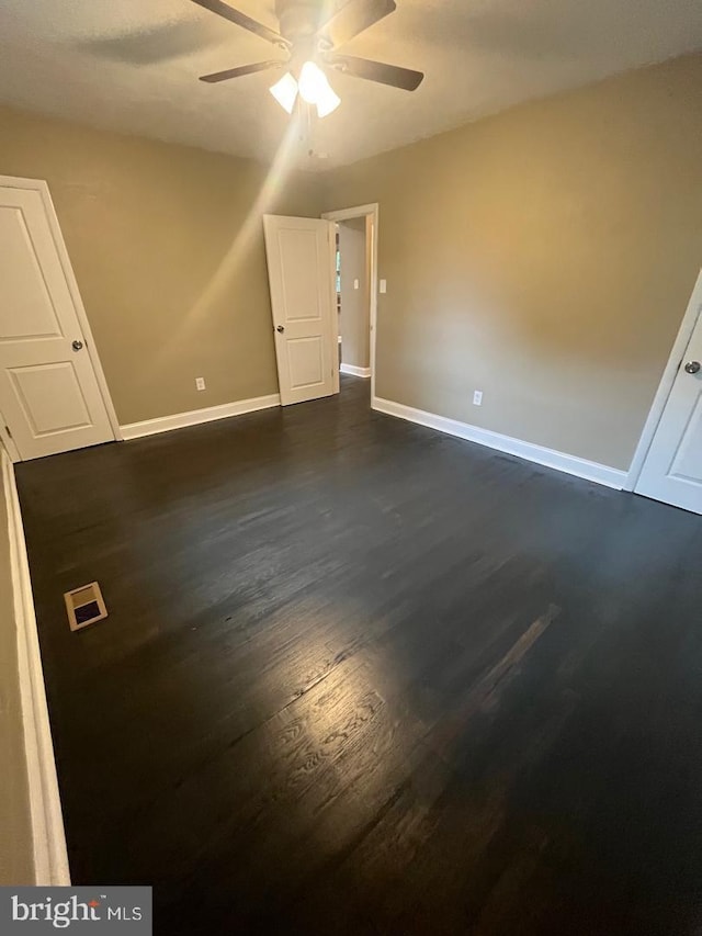 empty room with ceiling fan and dark wood-type flooring