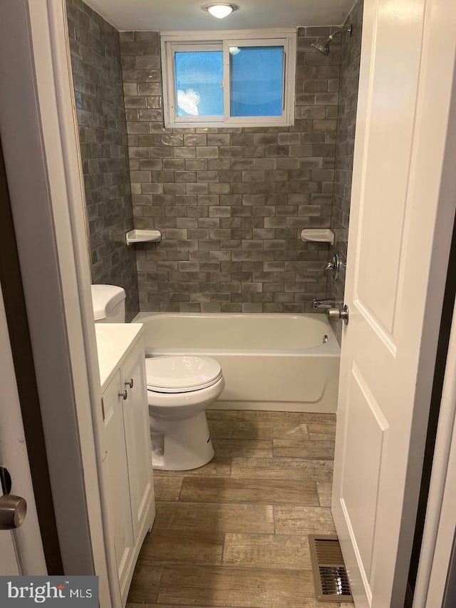 full bathroom featuring tiled shower / bath, hardwood / wood-style flooring, vanity, and toilet