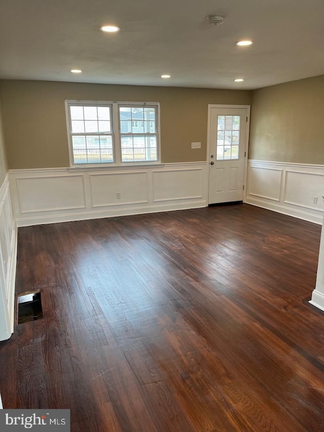 unfurnished room with a healthy amount of sunlight and dark wood-type flooring