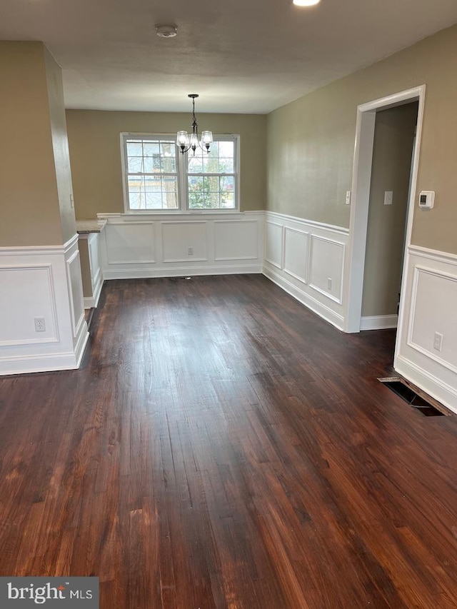 unfurnished dining area featuring dark hardwood / wood-style flooring and a chandelier