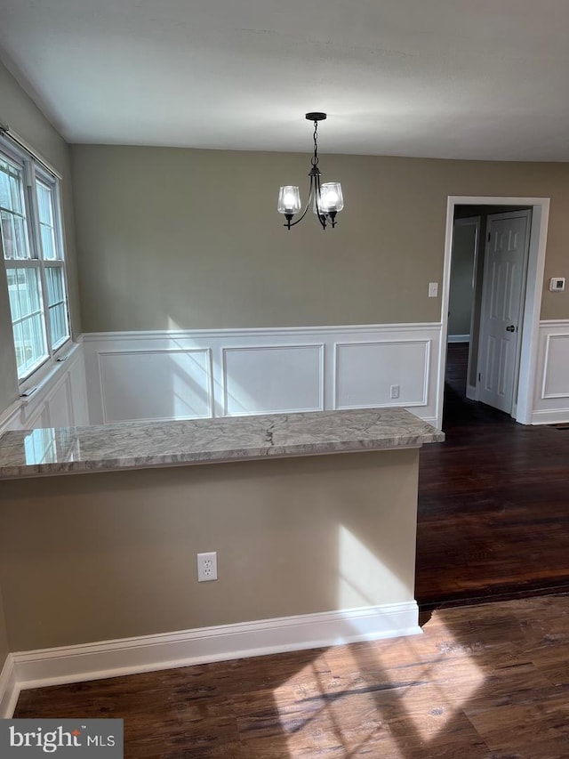 interior space with a chandelier, pendant lighting, dark hardwood / wood-style flooring, and light stone counters