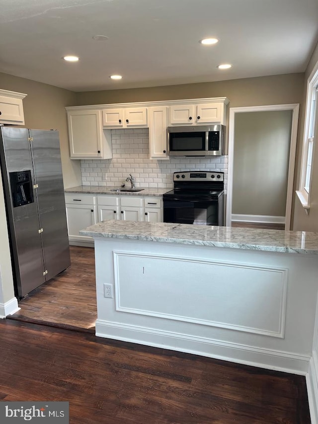 kitchen featuring white cabinetry, sink, light stone countertops, dark wood-type flooring, and appliances with stainless steel finishes