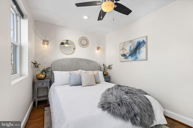 bedroom featuring multiple windows, dark hardwood / wood-style floors, and ceiling fan