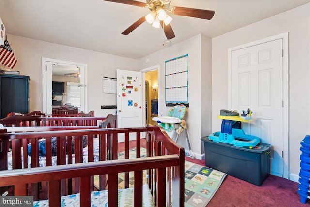 carpeted bedroom with ceiling fan and a nursery area