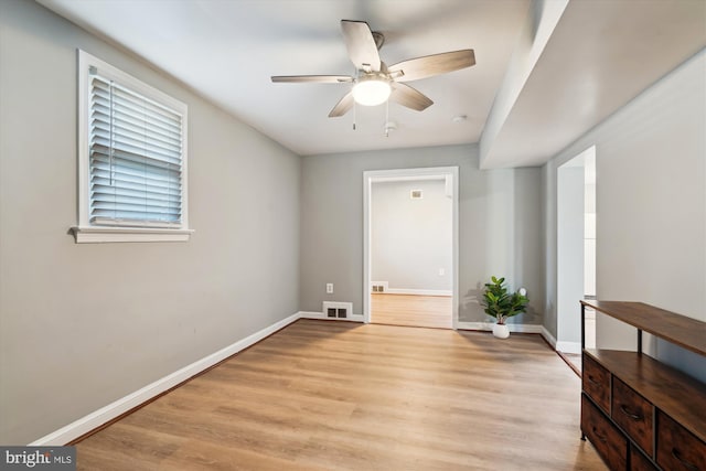 empty room with ceiling fan and light hardwood / wood-style flooring