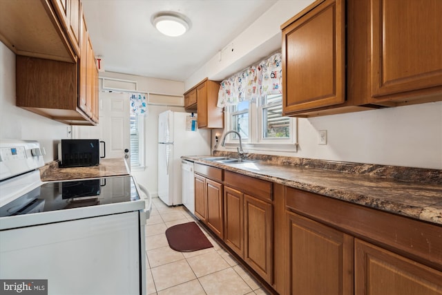 kitchen with white appliances, sink, light tile patterned floors, and dark stone counters