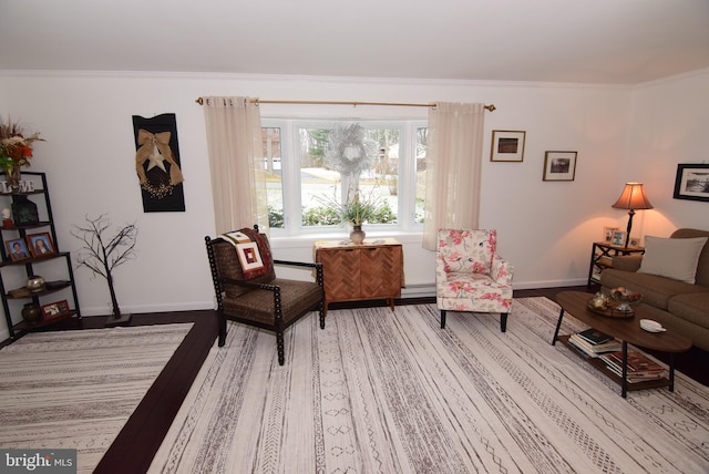 sitting room featuring wood-type flooring, a baseboard radiator, and crown molding