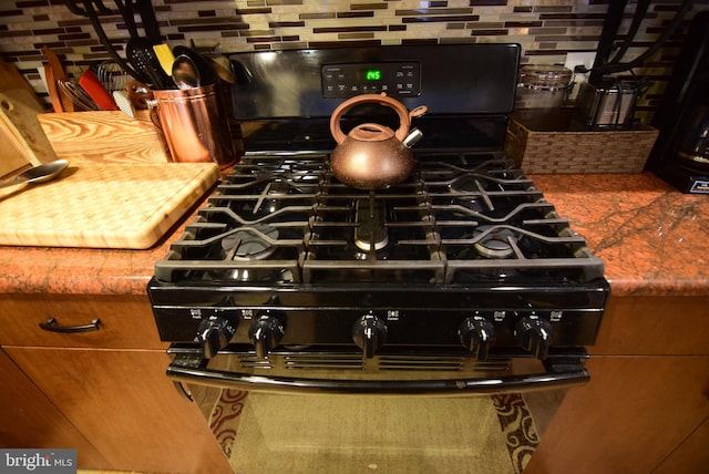 room details with decorative backsplash and gas stove