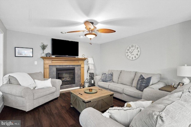 living room with dark hardwood / wood-style flooring, ceiling fan, and a tiled fireplace