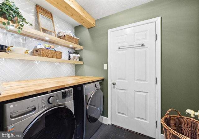 washroom with independent washer and dryer, a textured ceiling, and dark tile patterned floors