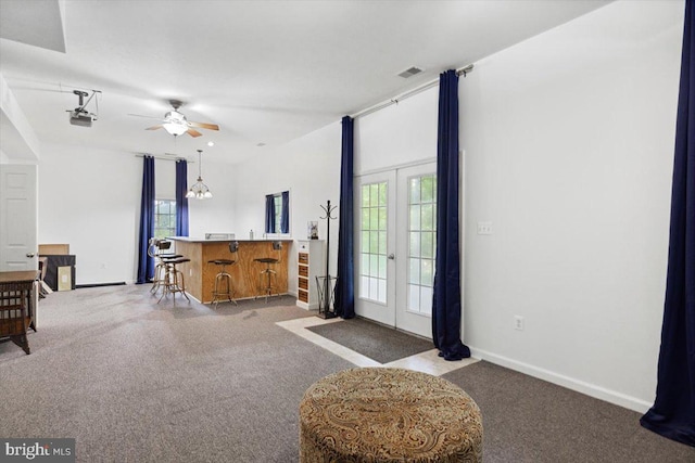 living room featuring french doors, ceiling fan with notable chandelier, light colored carpet, and plenty of natural light