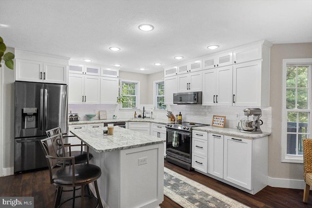 kitchen with a center island, white cabinets, stainless steel appliances, and sink