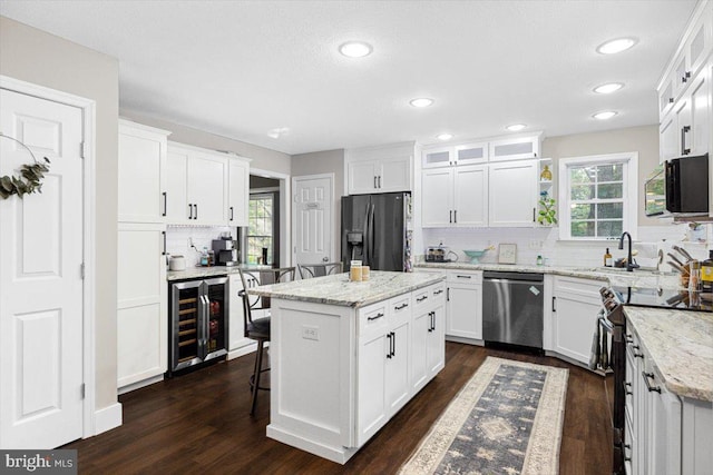 kitchen with white cabinetry, a center island, beverage cooler, tasteful backsplash, and appliances with stainless steel finishes