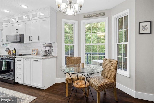 kitchen with light stone countertops, white cabinetry, stainless steel electric range oven, and a notable chandelier