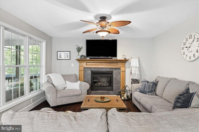 living room featuring ceiling fan, dark wood-type flooring, and a tiled fireplace