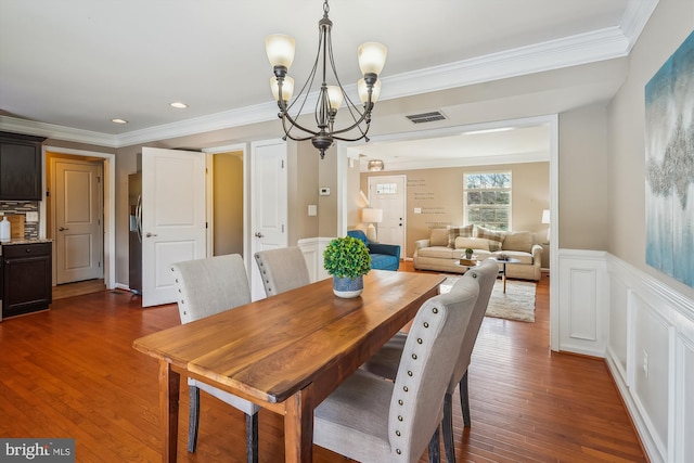 dining room with dark hardwood / wood-style flooring, crown molding, and an inviting chandelier