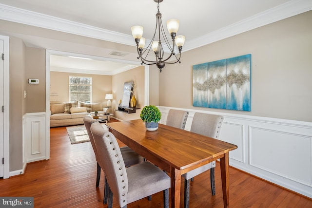 dining space featuring hardwood / wood-style flooring, crown molding, and an inviting chandelier