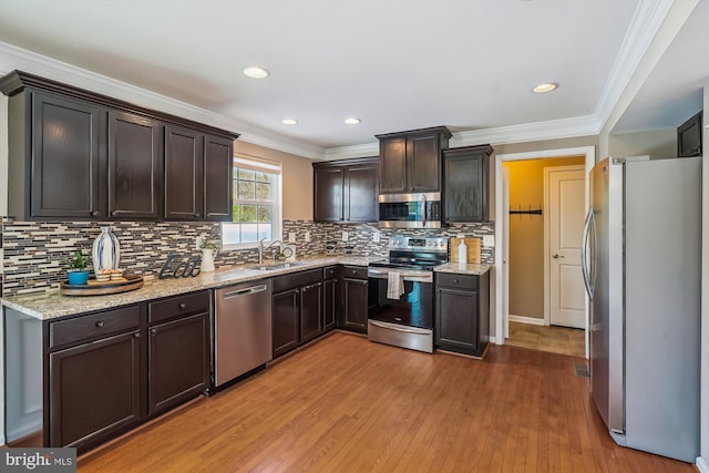 kitchen with appliances with stainless steel finishes, dark brown cabinetry, crown molding, and sink