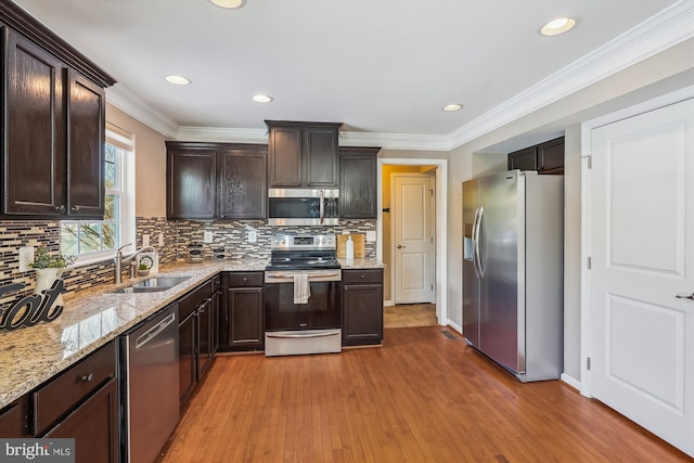 kitchen featuring dark brown cabinetry, decorative backsplash, light hardwood / wood-style flooring, and stainless steel appliances