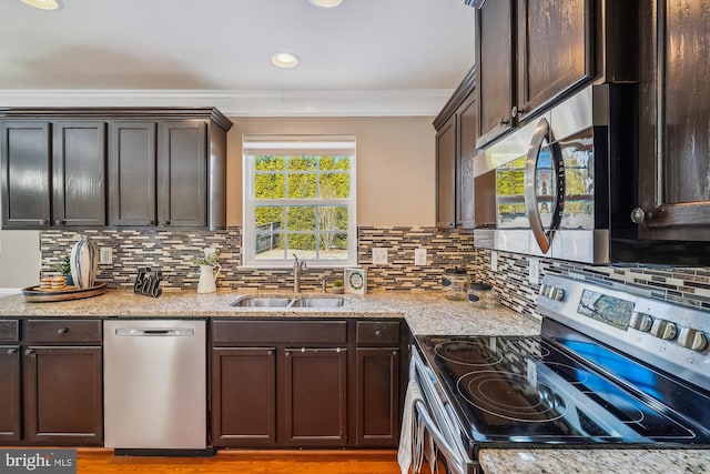 kitchen with sink, appliances with stainless steel finishes, tasteful backsplash, light stone counters, and dark brown cabinetry