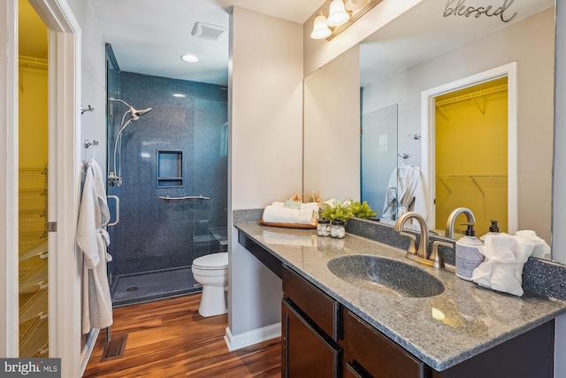 bathroom featuring vanity, toilet, wood-type flooring, and tiled shower