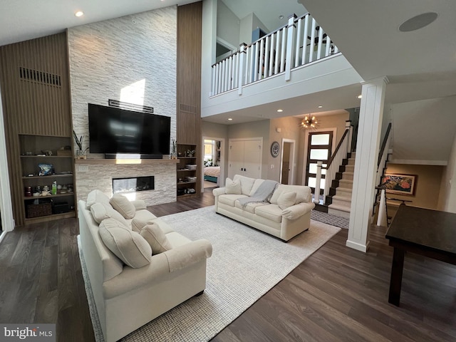 living room featuring a fireplace, a high ceiling, dark hardwood / wood-style flooring, and a chandelier