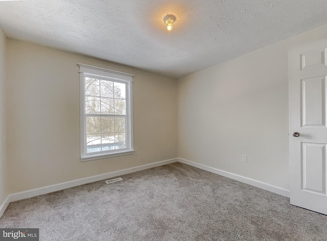 empty room featuring a textured ceiling and carpet