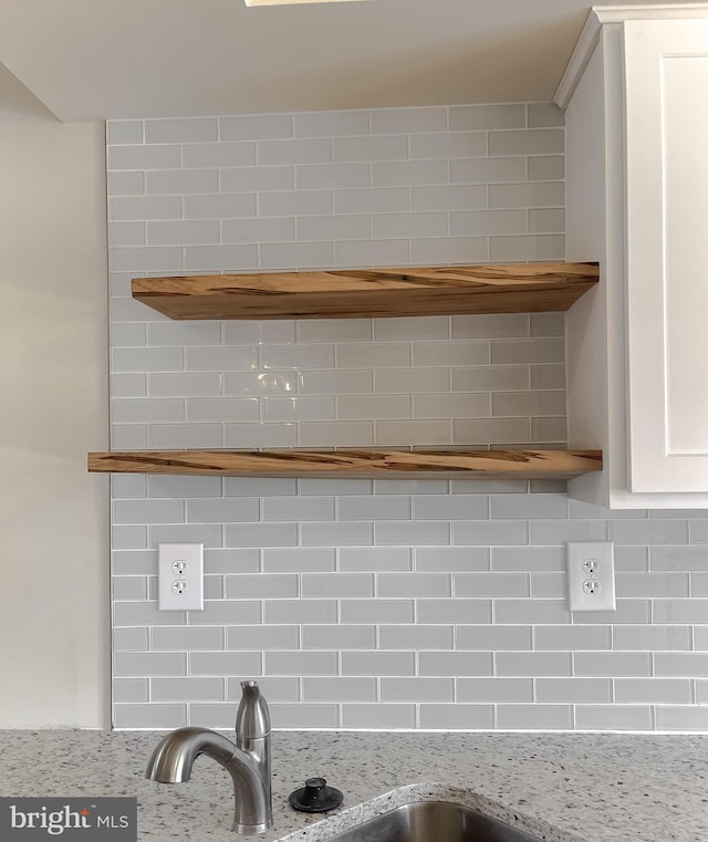 room details with white cabinets, tasteful backsplash, and light stone countertops