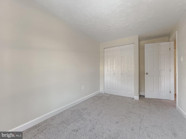 unfurnished bedroom featuring light colored carpet, a closet, and a textured ceiling